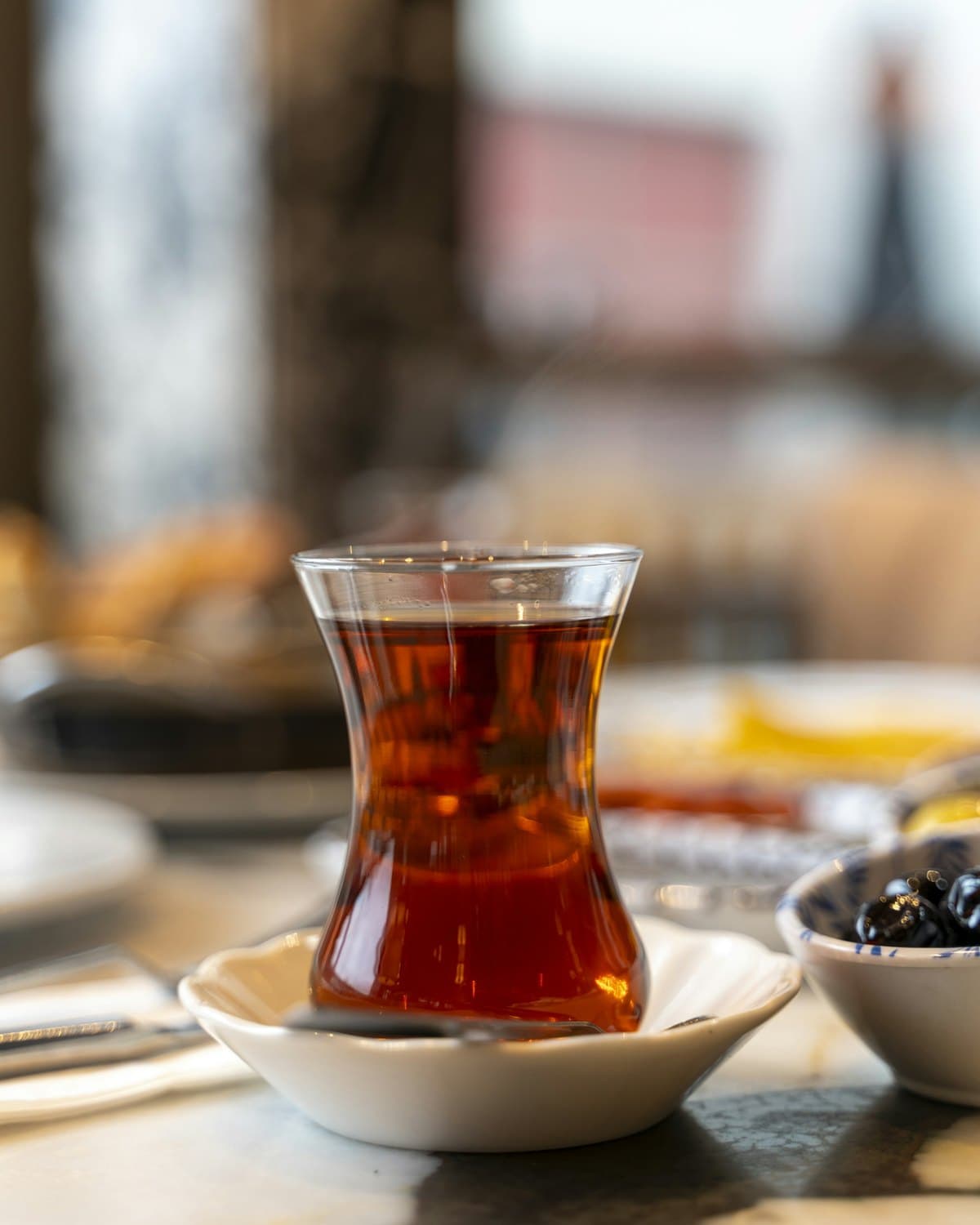 Turkish tea in a tulip-shaped glass on a saucer, held up to the light.